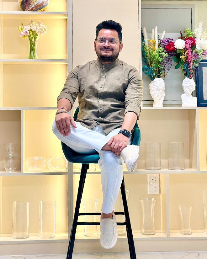 Vivek Dubey, founder and digital marketing expert, seated in a modern office with floral décor and illuminated shelves.